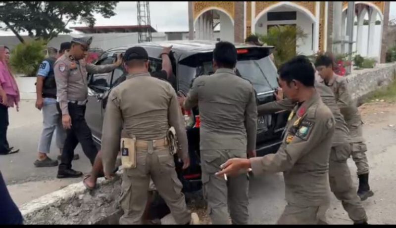 Kanit Regident Bulukumba, Iptu Malkadri Ibrahim, membantu warga mendorong mobil yang terperosok di depan Stadion Mini Bulukumba.