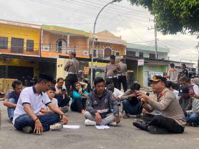 Kapolres Bulukumba AKBP Restu Wijayanto duduk lesehan bersama massa Aliansi Pemuda Sapobonto saat menerima aksi unjuk rasa terkait kasus pencurian sapi di depan Mapolres Bulukumba, Senin 27 April 2026.